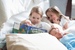 siblings reading to new baby