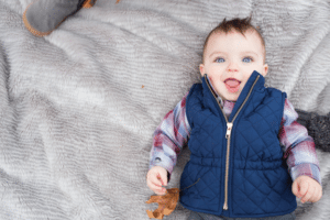 baby in blue vest holding a leaf