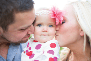 parents kissing baby girl