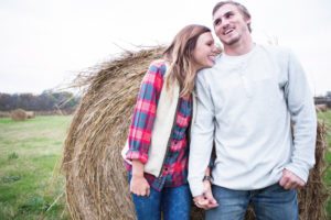 couple holding hands in front of barn