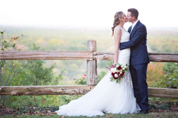 Wedding kiss in front of fence