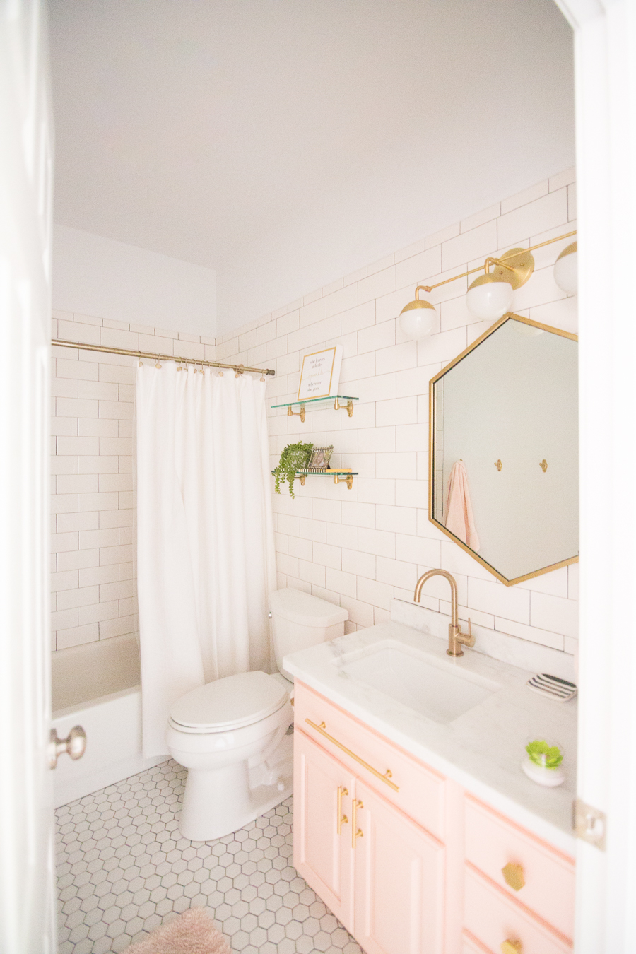 Modern Glam Blush Girls Bathroom Design Gold Hexagon Mirror Blush Cabinets Gold Hardware White Hexagon Floor Glass Shelves Pink Bathroom Cabinets Gold Orb Sconce 4 3 Cc Mike