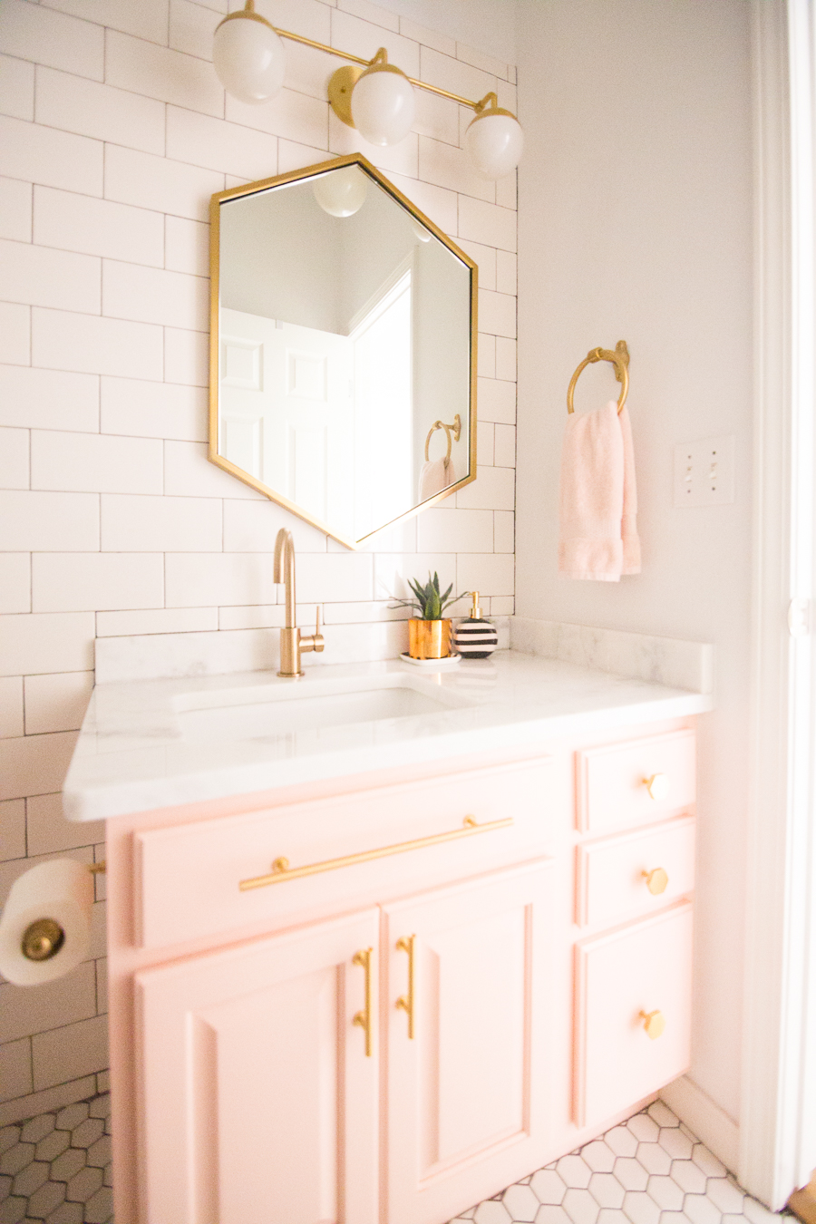 Modern Glam Blush Girls Bathroom Design gold hexagon mirror blush cabinets gold hardware white hexagon floor glass shelves pink bathroom cabinets gold orb sconce-1-3