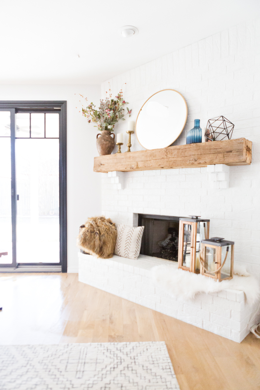 Tulsa Remodel Reveal Modern White Farmhouse black windows and doors white brick fireplace wood beam mantle gold round mirror-1