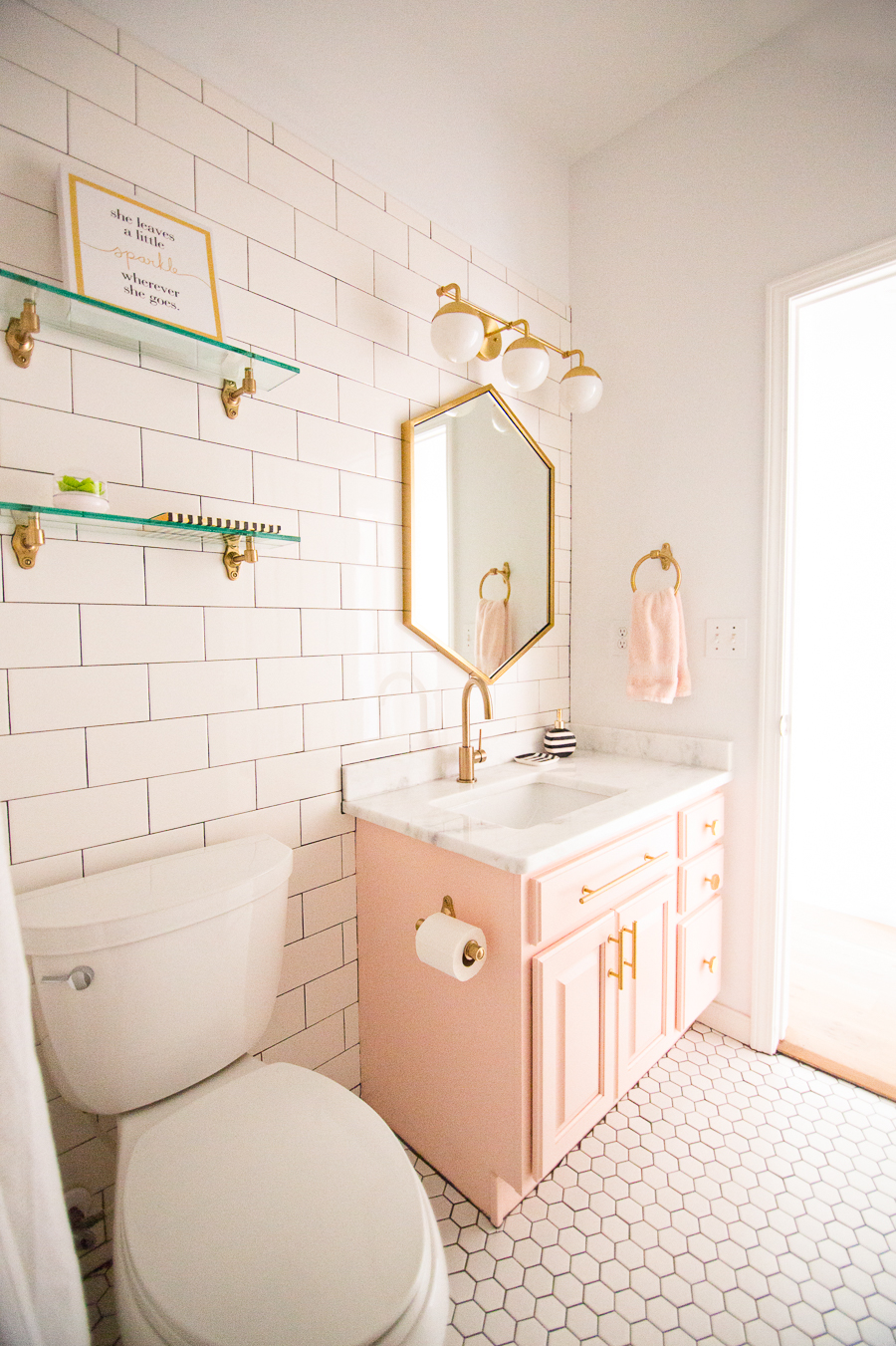 Tulsa Remodel Reveal Modern White Farmhouse modern glam pink girls bathroom gold hexagon mirror blush cabinet gold hardware white hexagon floors glass floating shelves-1