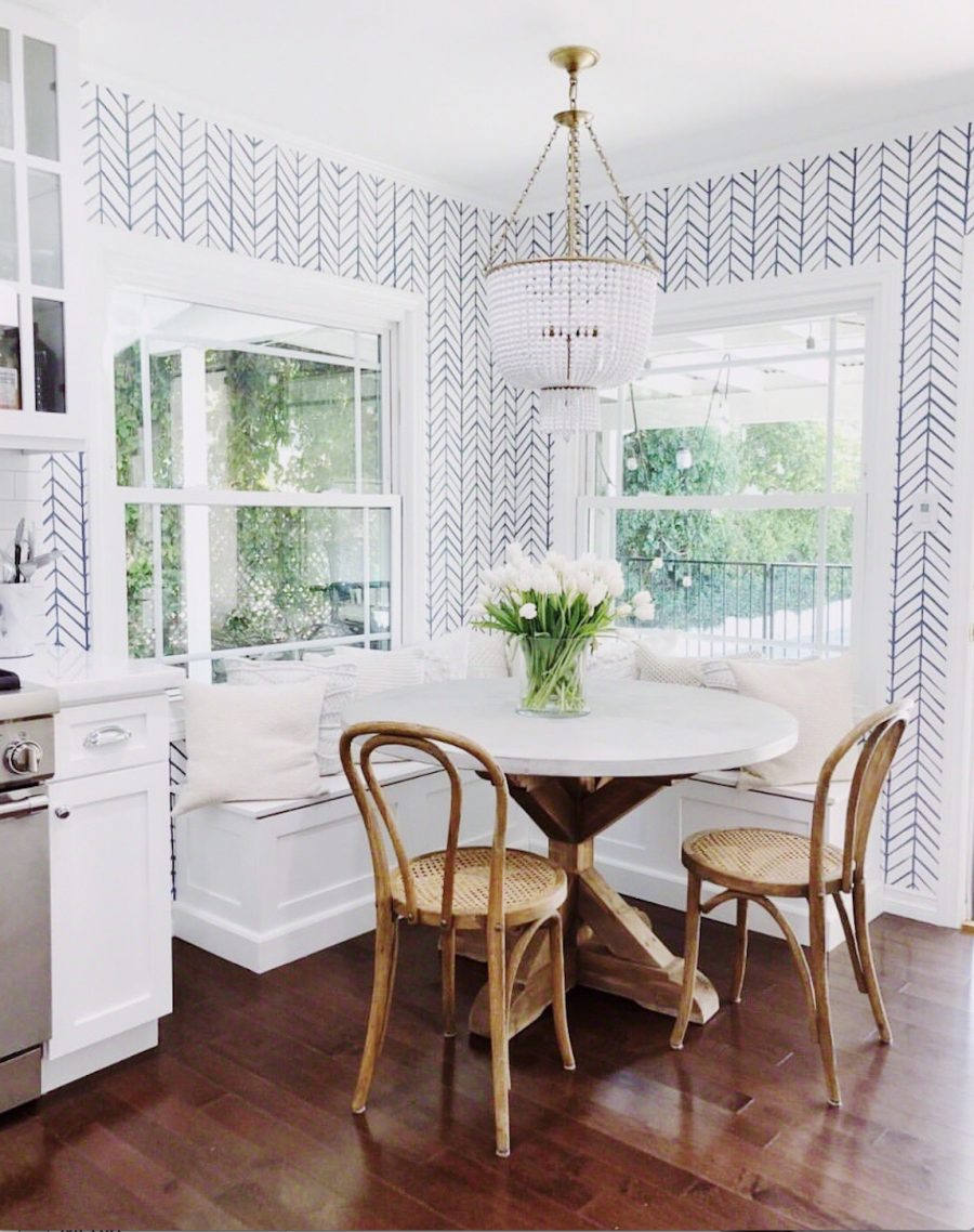 https://ccandmike.com/wp-content/uploads/2018/03/How-to-Design-A-Beautiful-Kitchen-Banquette-White-round-table-wood-legs-wood-farmhouse-chairs-beaded-chandelier-light-fixture-serena-and-lily-wallpaper-e1523908475845.jpg