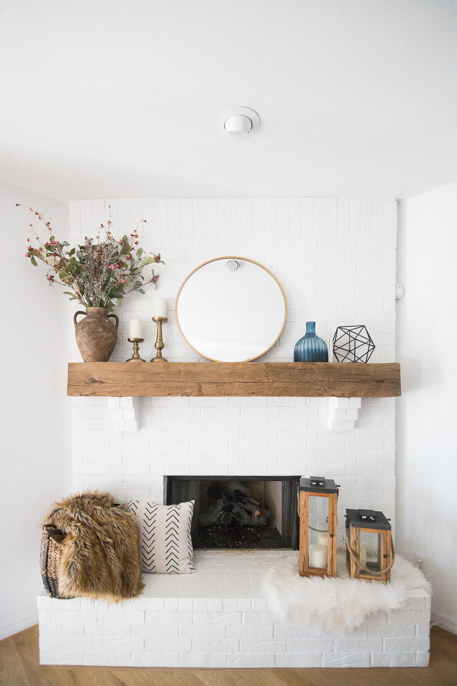 White Painted Brick Fireplace Makeover TV collage wall pottery barn wood media console article sven leather sofa faux fiddle leaf fig tree wood lanterns round gold mirror fireplace styling white walls black windows