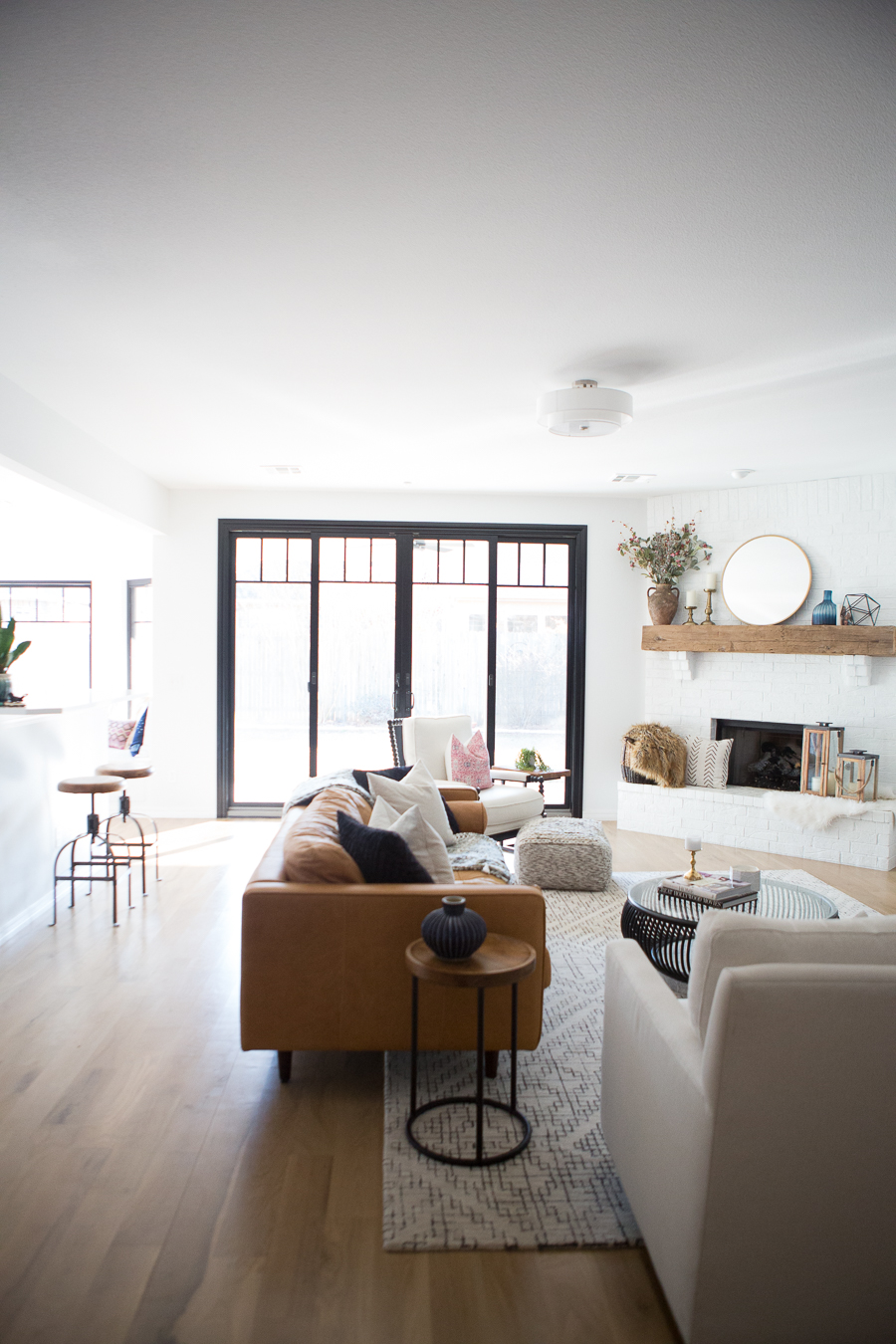 White Painted Brick Fireplace Makeover TV collage wall pottery barn wood media console article sven leather sofa faux fiddle leaf fig tree wood lanterns round gold mirror fireplace styling white walls black windows