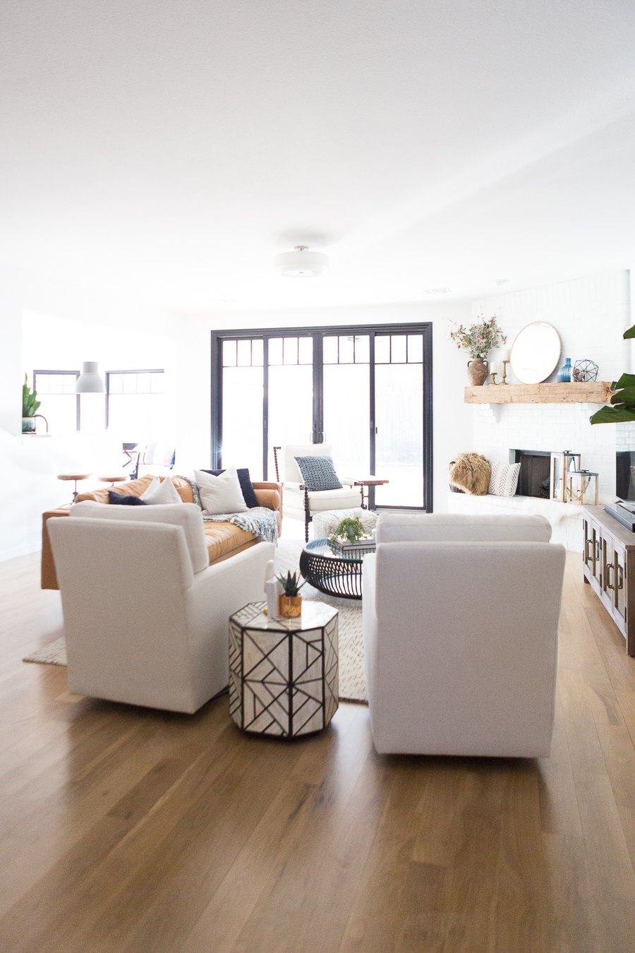 White Painted Brick Fireplace Makeover TV collage wall pottery barn wood media console article sven leather sofa faux fiddle leaf fig tree wood lanterns round gold mirror fireplace styling white walls black windows