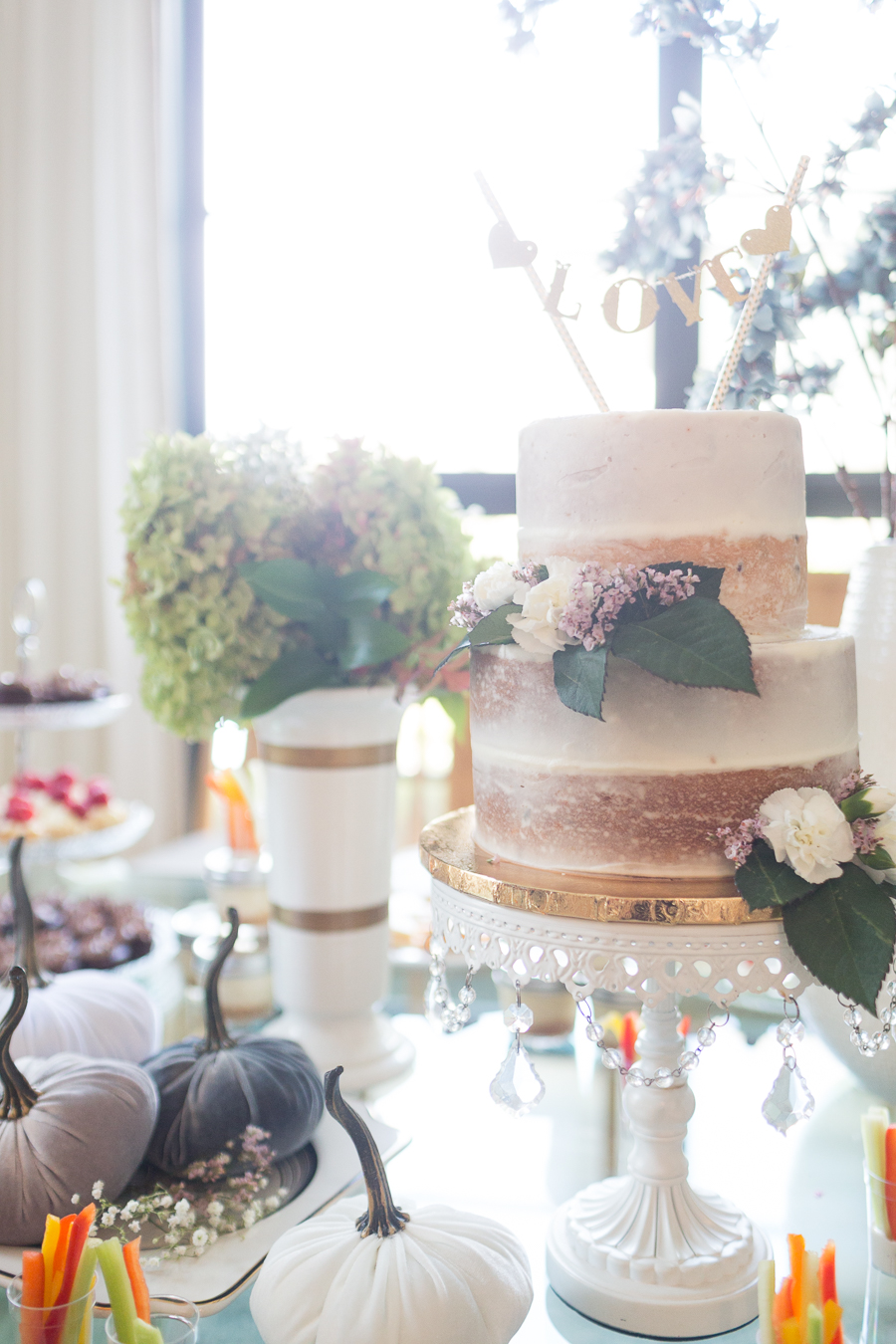 Beautiful Fall Bridal Shower Ideas fall bridal shower cake on a white cake stand surrounded by velvet pumpkins and hydrangeas