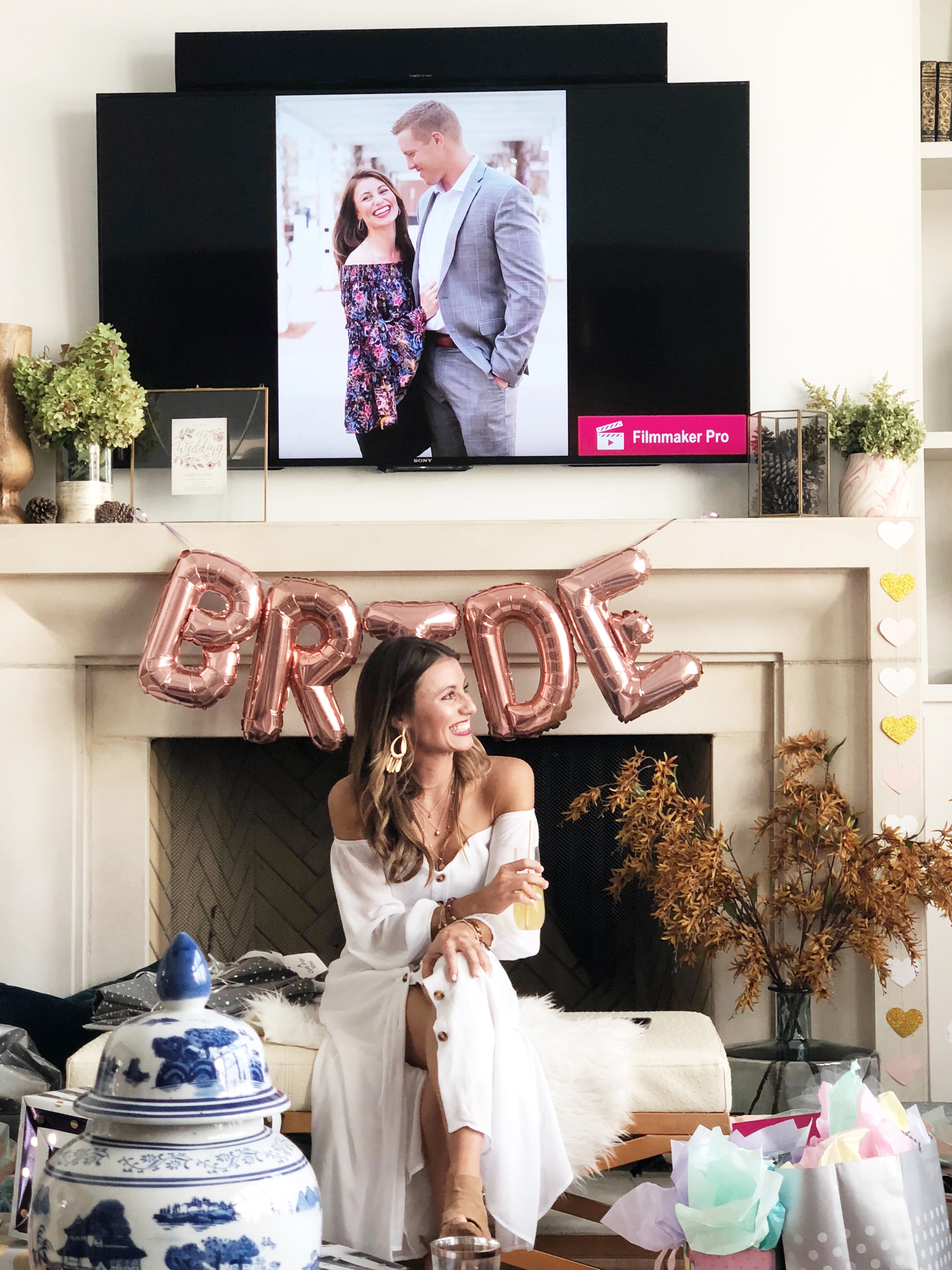 Beautiful Fall Bridal Shower Ideas bride to be in an off the shoulder button up dress holding a rose colored balloon bouquet at her bridal shower playing the newlywed game