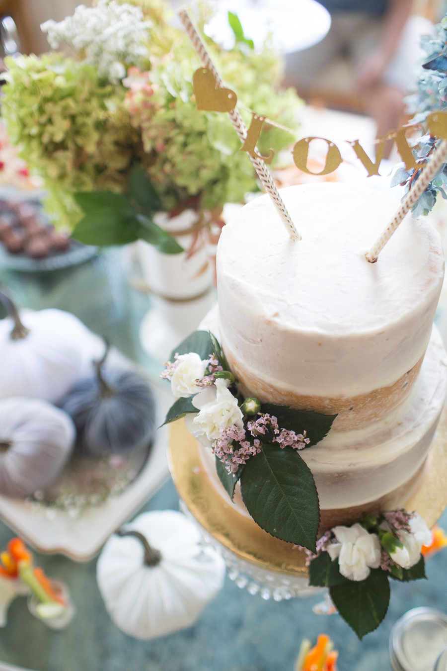 Beautiful Fall Bridal Shower Ideas fall bridal shower cake on a white cake stand surrounded by velvet pumpkins and hydrangeas