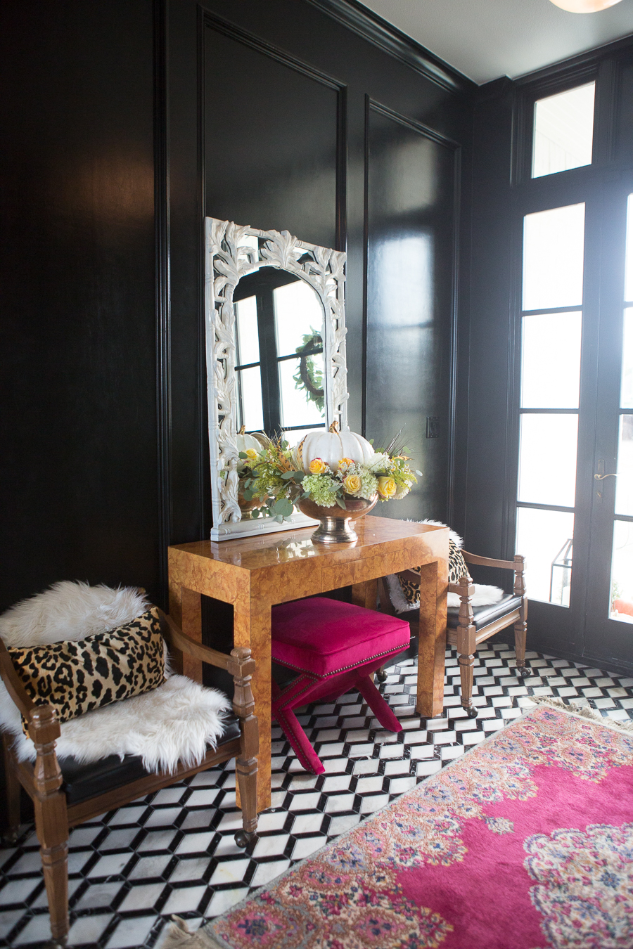 Loveliest Looks of Fall Home Tour Beautiful Fall Home Decor and Fall Fashion Ideas entryway with black paneling painted high gloss and marble black and white floors with a burl wood console table and a white mirror hanging about it and a silver urn floral pumpkin centerpiece sitting on the table