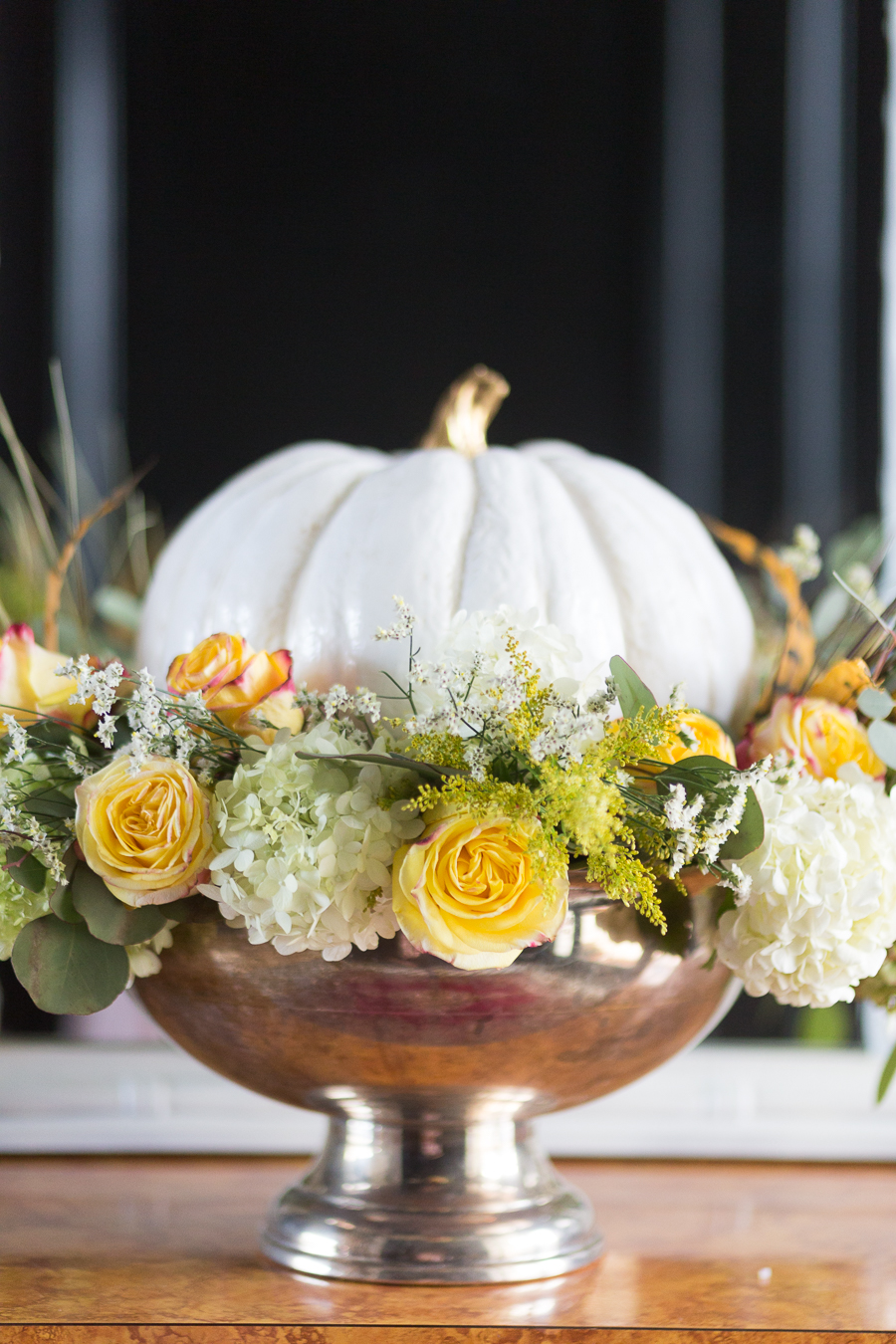 Loveliest Looks of Fall Home Tour Beautiful Fall Home Decor and Fall Fashion Ideas entryway with black paneling painted high gloss and marble black and white floors with a burl wood console table and a white mirror hanging about it and a silver urn floral pumpkin centerpiece sitting on the table