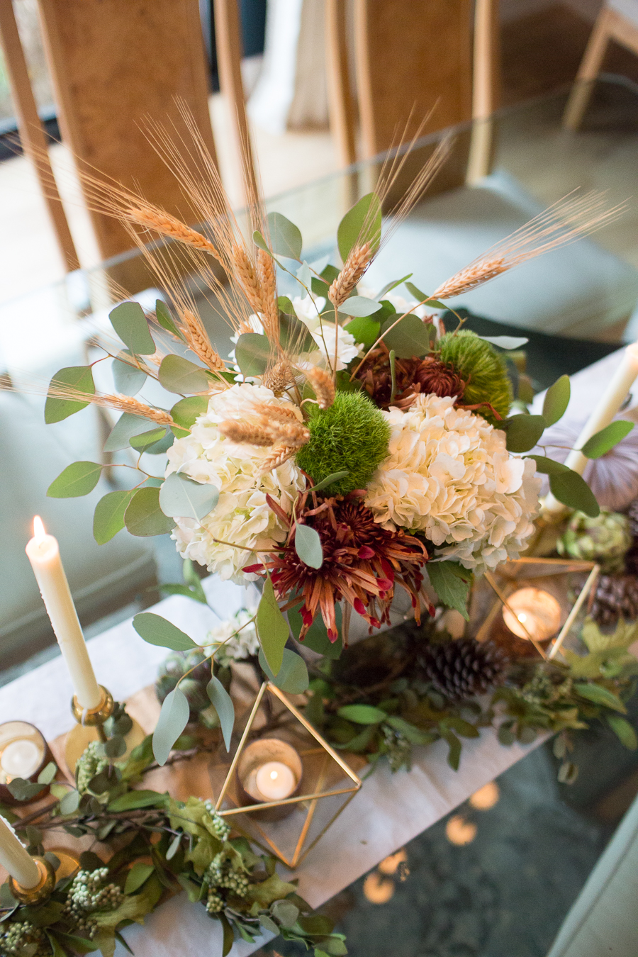 Simple Ways to Decorate for the Holidays from West Elm dark green painted dining room with glass and gold marble dining room table and burl wood chairs with a holiday tablescape with gold candlesticks and a large silver faceted vase with fresh flowers