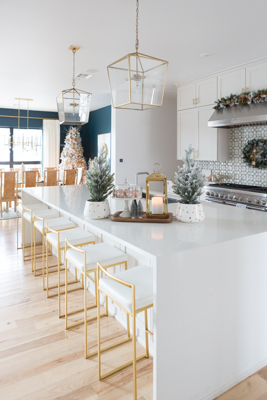 Budget Friendly Holiday Decor from Walmart white quartz waterfall island with gold bar stools and gold lanterns and a wood tray with a gold lantern and flocked Christmas trees in a polka dot vase