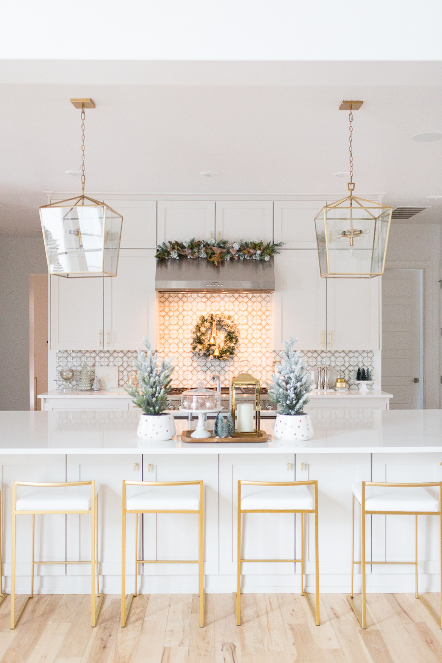 Budget Friendly Holiday Decor from Walmart white quartz waterfall island with gold bar stools and gold lanterns and a wood tray with a gold lantern and flocked Christmas trees in a polka dot vase