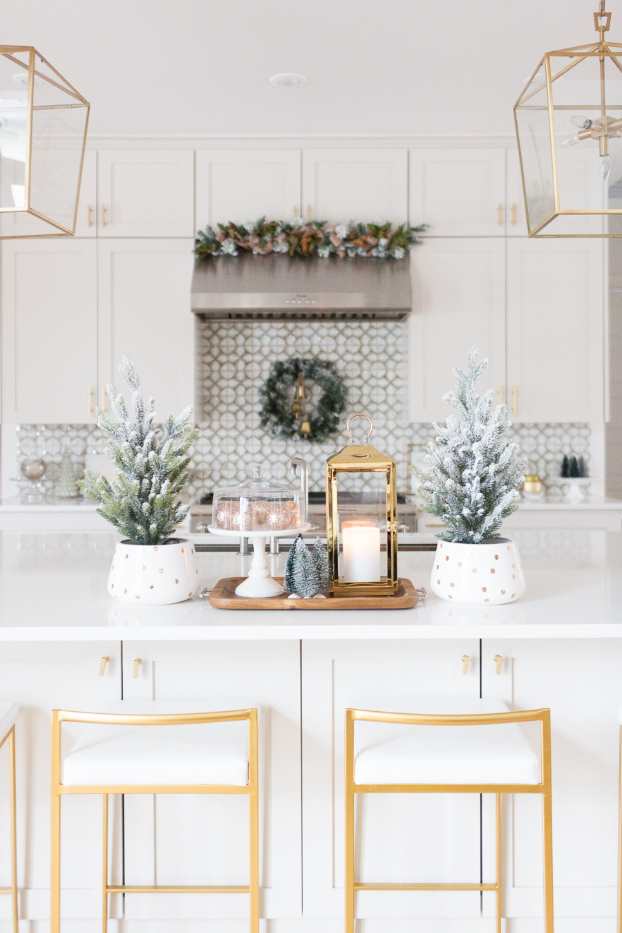 Budget Friendly Holiday Decor from Walmart white quartz waterfall island with gold bar stools and gold lanterns and a wood tray with a gold lantern and flocked Christmas trees in a polka dot vase