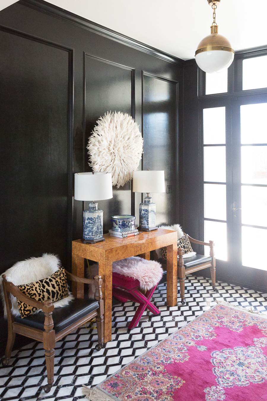 HOW TO FIND BLACK WINDOWS AND DOORS FOR LESS featured in the entry way of the home with a black accent wall and bright decor 