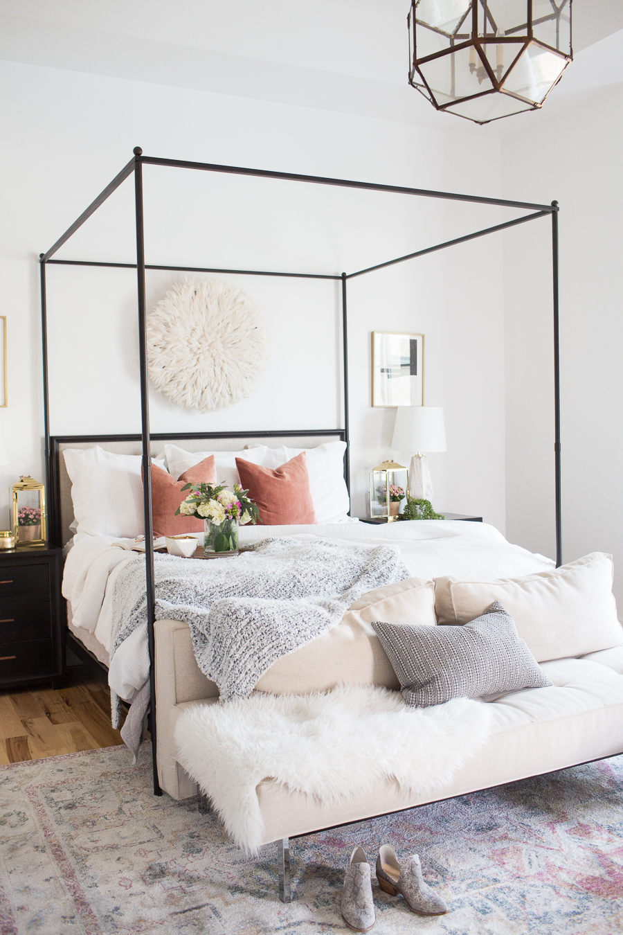 Refresh Your Master Bedroom and Bath with Pottery Barn featuring a black canopy bed with white clean white bedding and a fur throw blanket and grey throw blanket