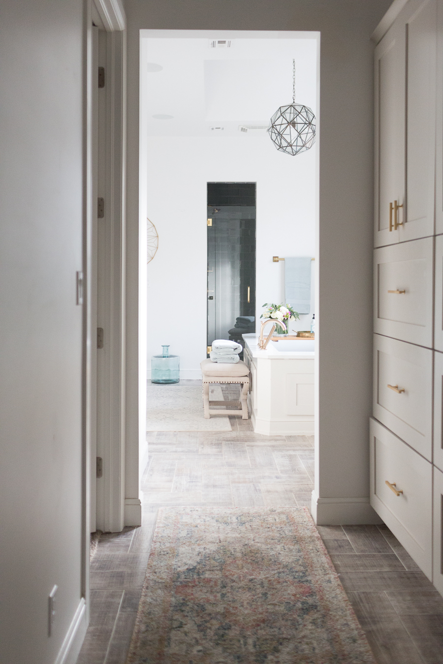Refresh Your Master Bedroom and Bath with Pottery Barn looking from the hallway into the white bathroom with multi-colored runner