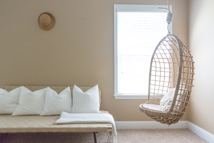 TEEN HANGOUT ROOM DESIGN PLAN AND HANGING CHAIRS with tan walls and a neutral aesthetic and white pillows in a line on the couch