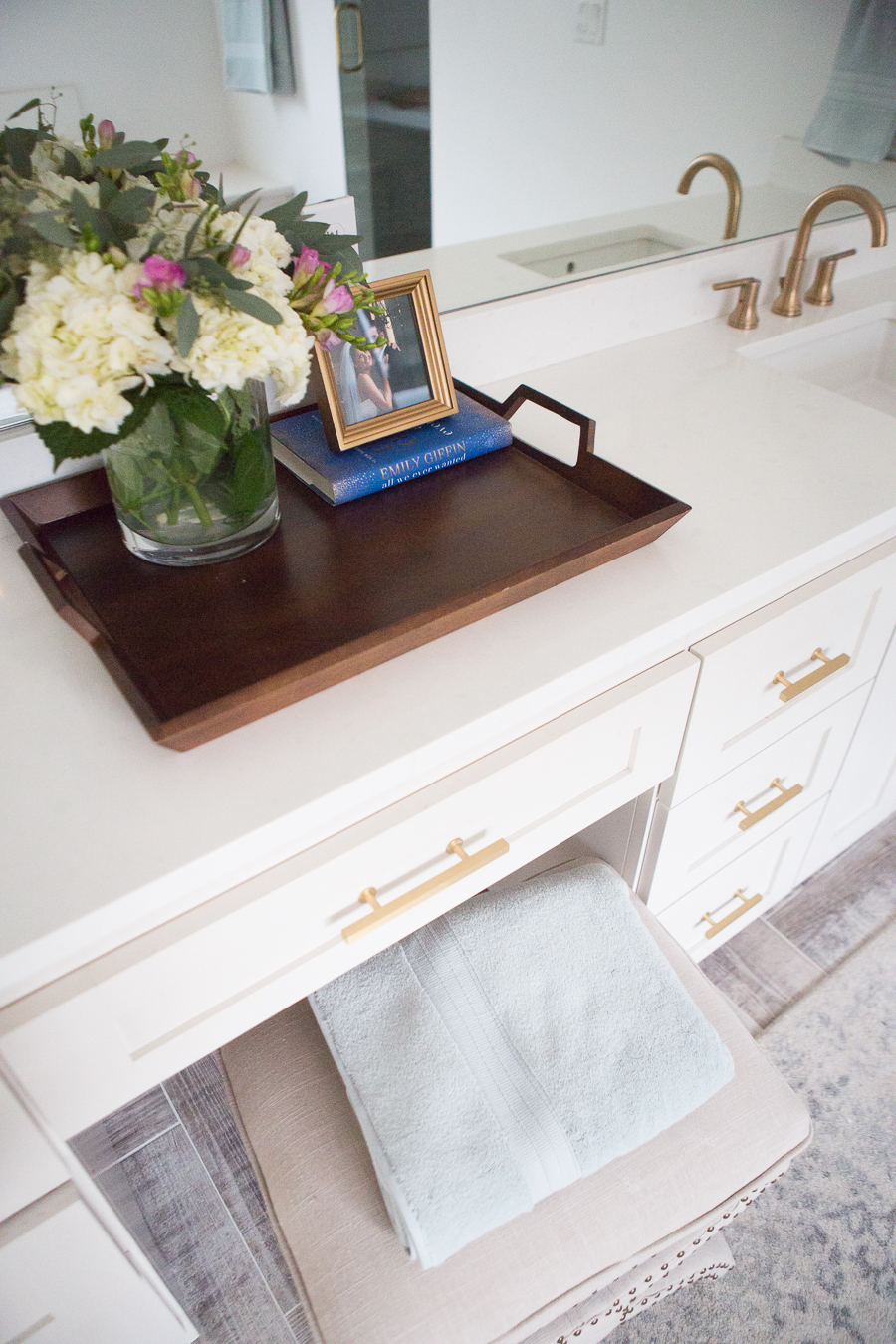 Refresh Your Master Bedroom and Bath with Pottery Barn white vanity with gold handle pulls and faucet and wooden tray with beautiful floral arrangement