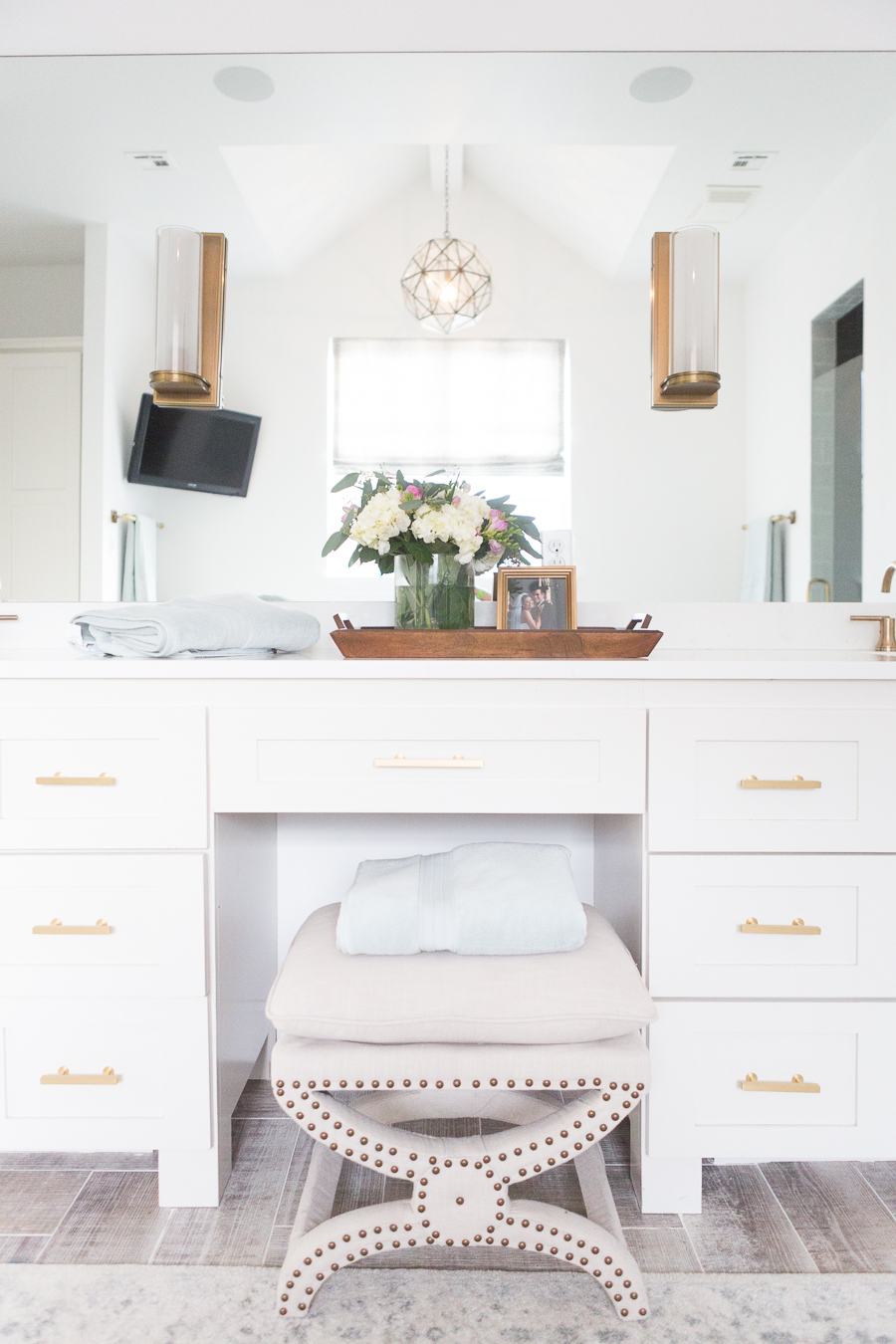 Refresh Your Master Bedroom and Bath with Pottery Barn white vanity with gold sconces and handle pulls with studded stool and full wall mirror