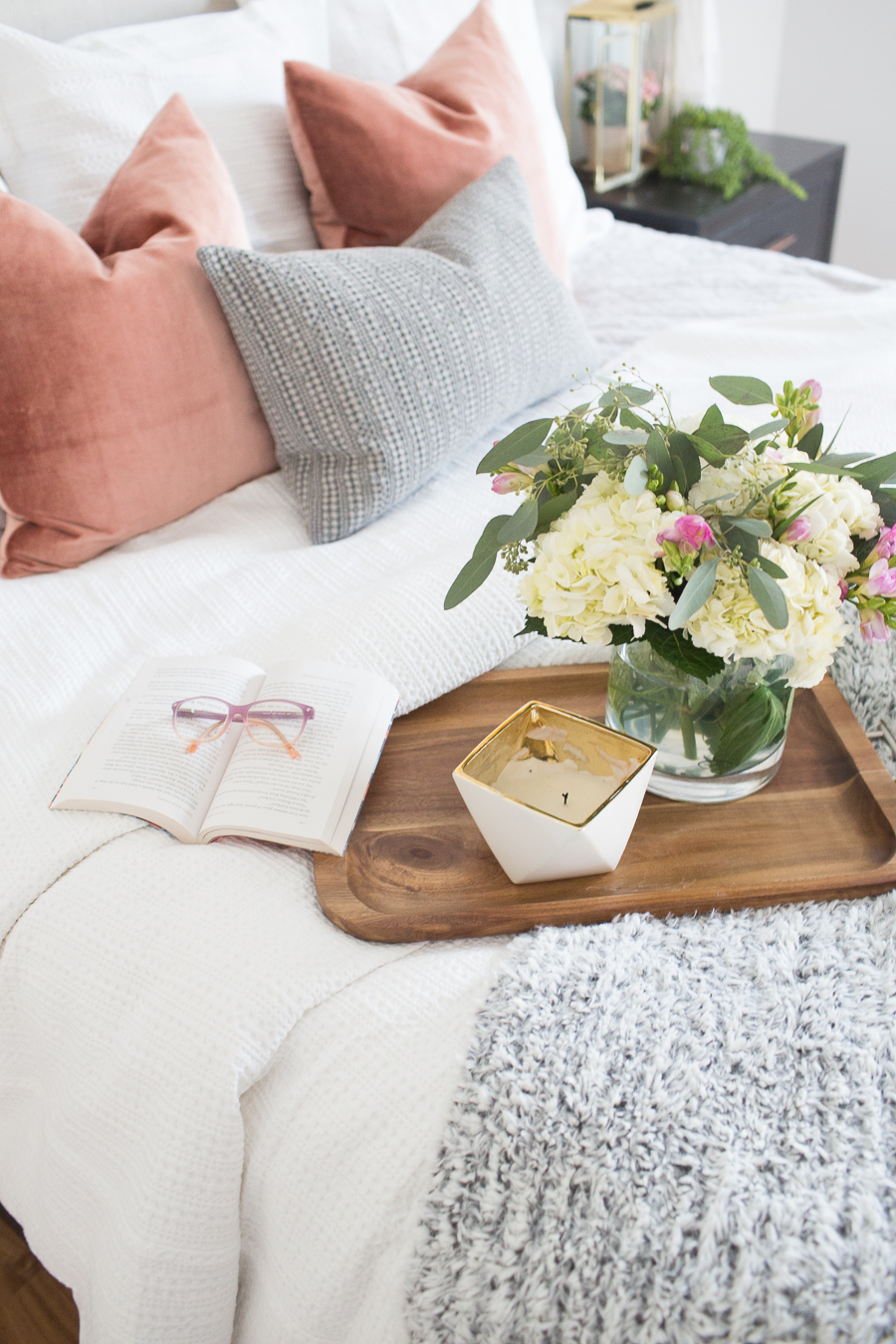 Refresh Your Master Bedroom and Bath with Pottery Barn closer view of the wooden tray and candle and hydrangeas with pastel colors on the bed