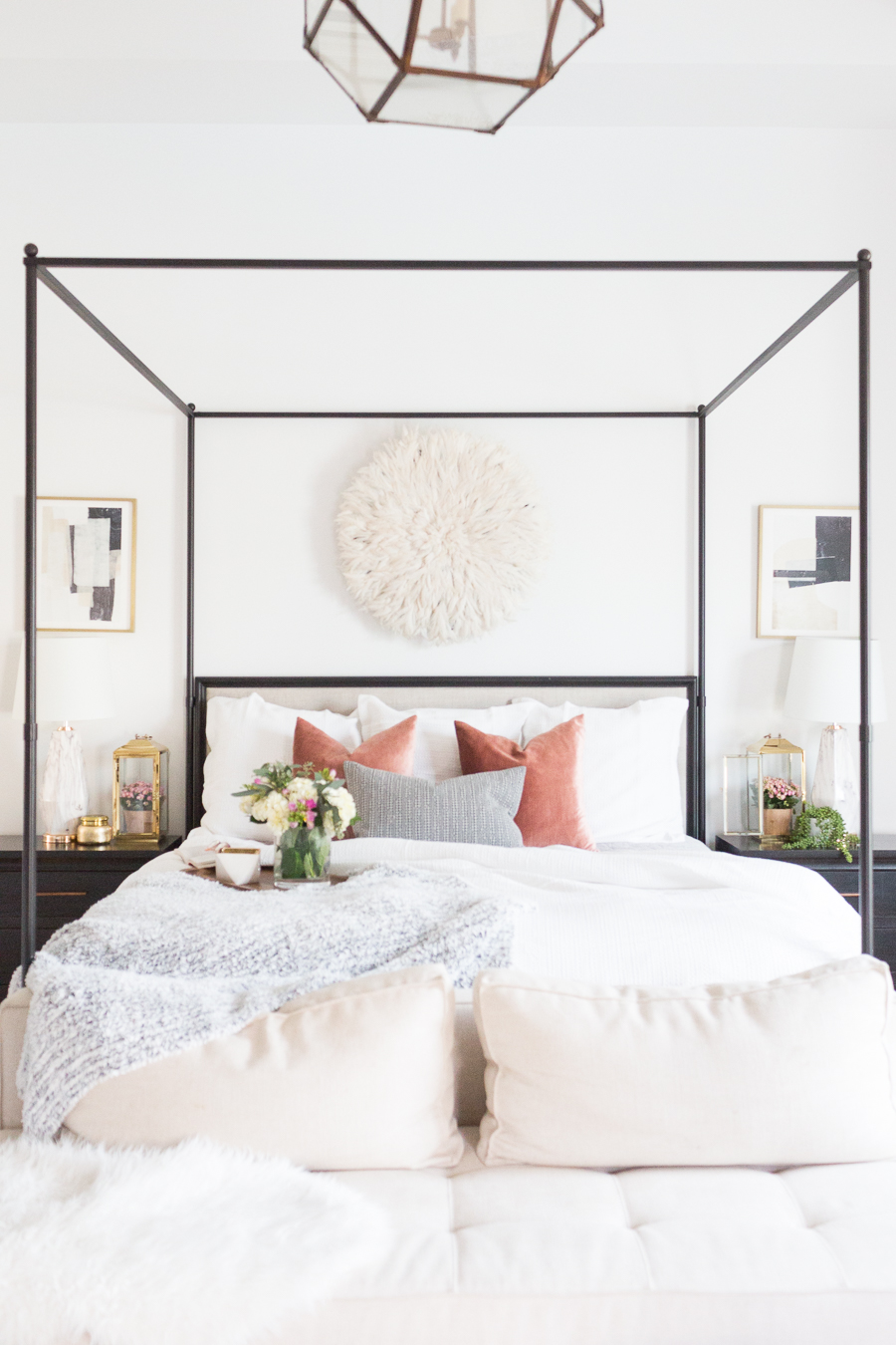 Refresh Your Master Bedroom and Bath with Pottery Barn black canopy bed with white bedding and pastel pillows with beautiful flowers in a vase