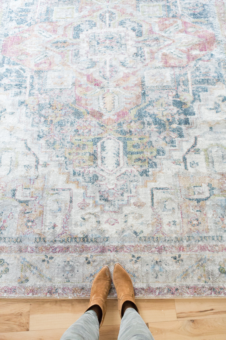 REFRESH YOUR MASTER BEDROOM AND BATH WITH POTTERY BARN looking down at tan booties onto a faded multicolored rug