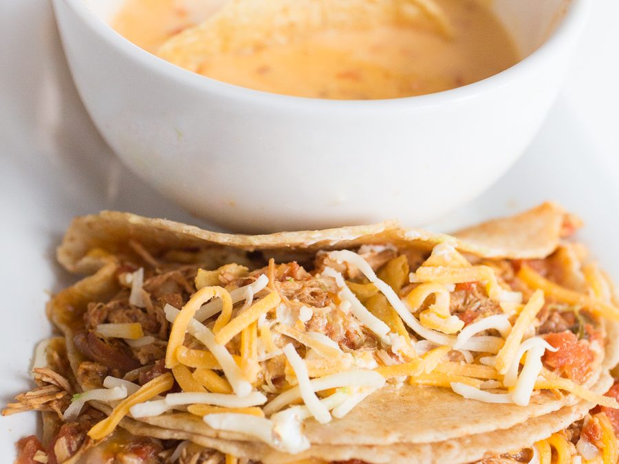 Two Minute Crockpot Chicken Ranch Tacos-1 soft tacos on a long white plate with a bowl of queso and chips