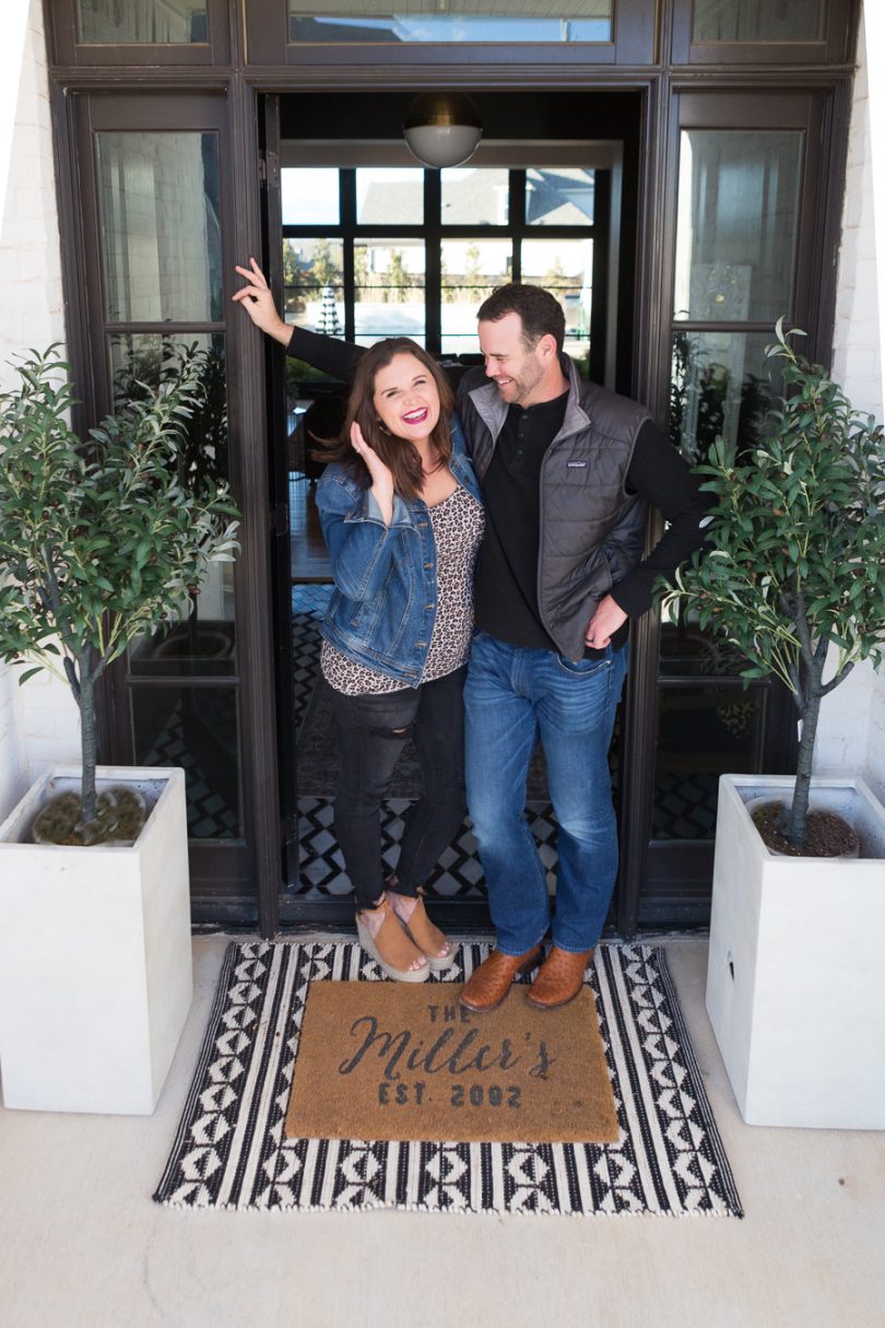 Easy Spring Front Porch Makeover Ideas CC and Mike standing on the front porch of their white brick modern home with black aluminum clad windows and doors -1