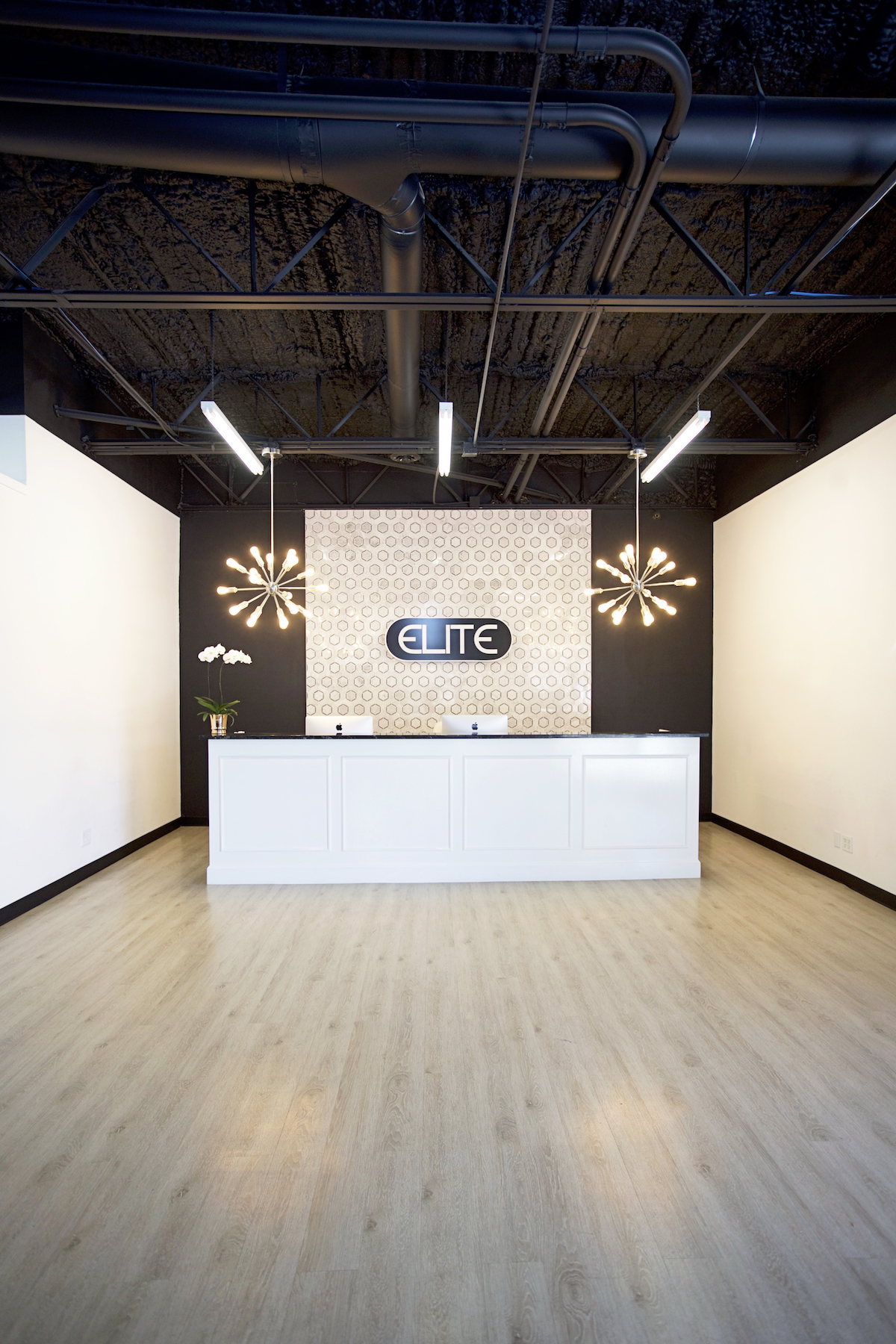 elite dance studio far back shot of the entire front desk, hexagon tile backsplash and sputnik chandeliers