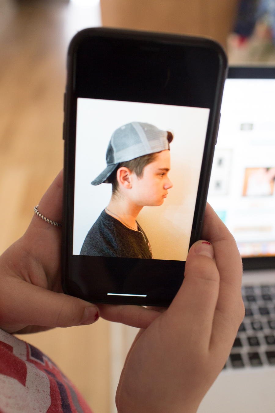 holding up an image on an iphone of a teenage boy profile