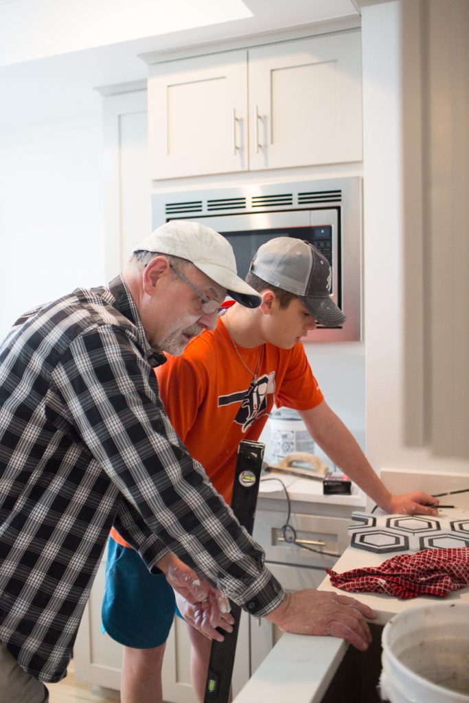 CC and Mike Teen Hangout Room Reveal with Joybird Sectional grandpa laying tile backsplash with his grandson