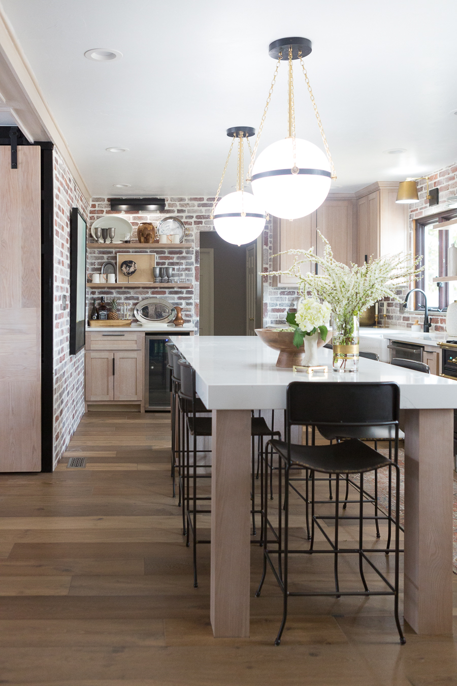 CC and Mike Kane Project Remodel Reveal brick kitchen bacskplash with a white farmhouse sink and black faucet rift sawn white oak cabinets with black hardware