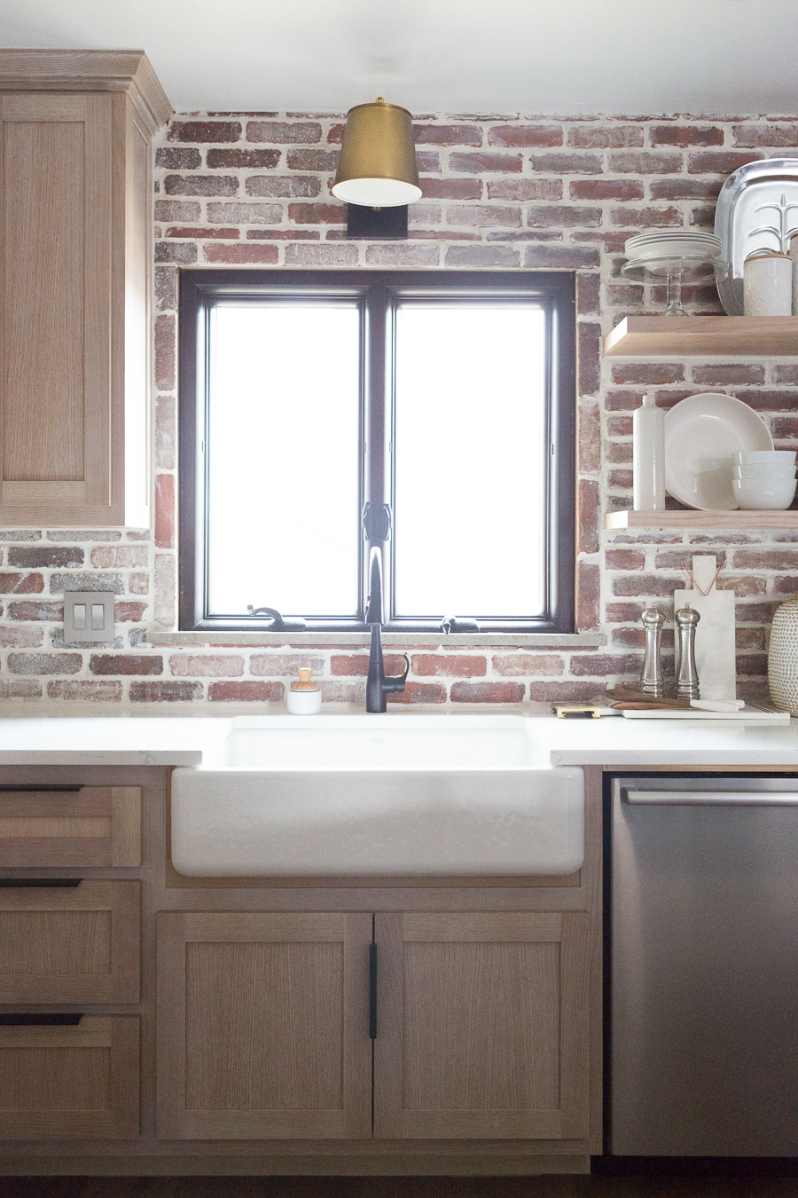 CC and Mike Kane Project Remodel Reveal brick kitchen bacskplash with a white farmhouse sink and black faucet rift sawn white oak cabinets with black hardware