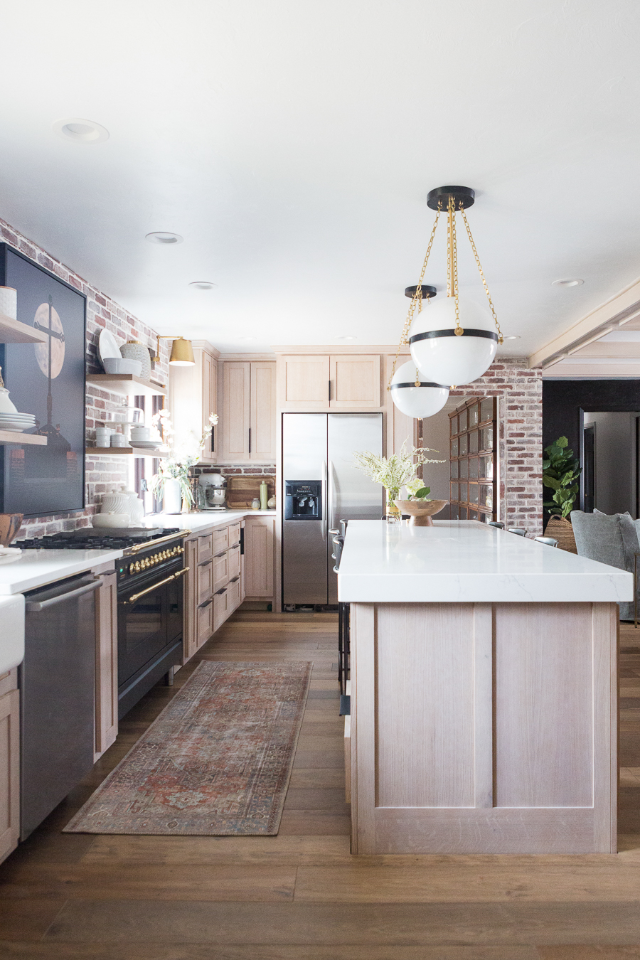 CC and Mike Kane Project Remodel Reveal rift sawn white oak wood kitchen cabinets with marble ountertops arteriors pendant lighting black hardware black stove with gold hardware loren kitchen runner