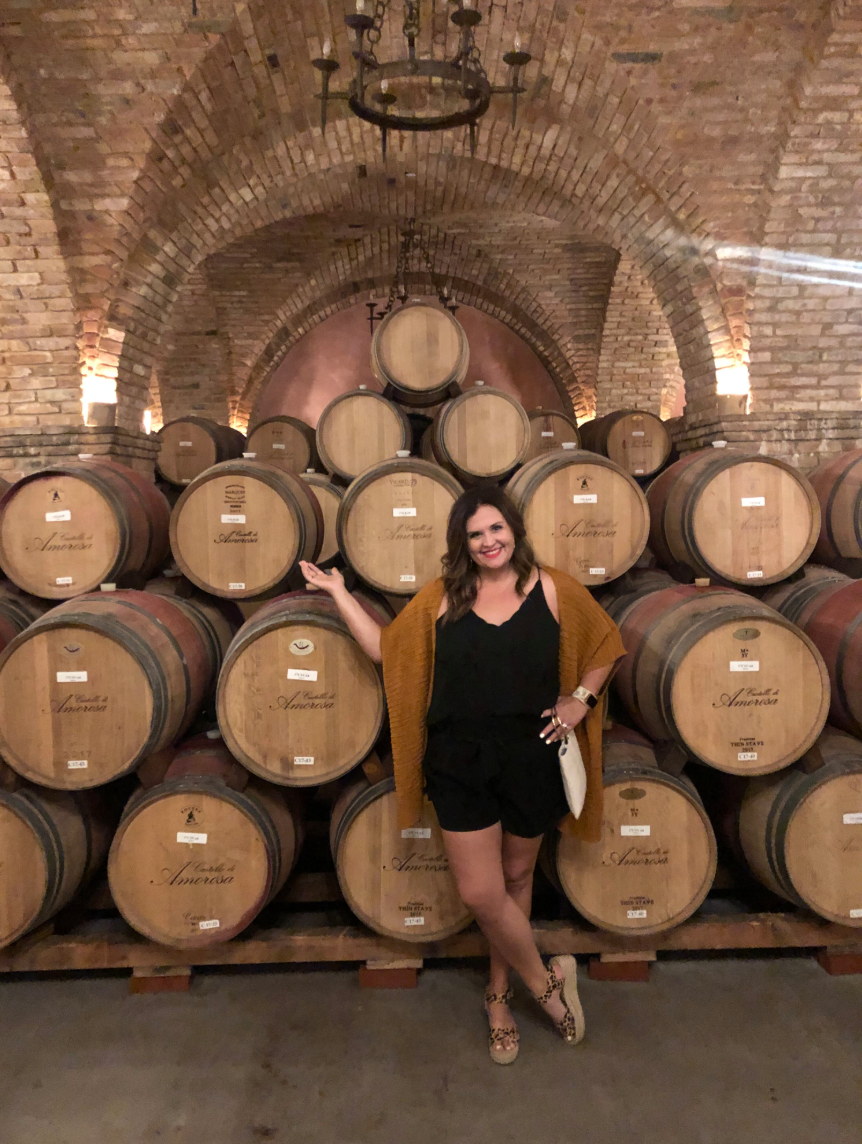 carissa standing in front of a bunch of wine barrels