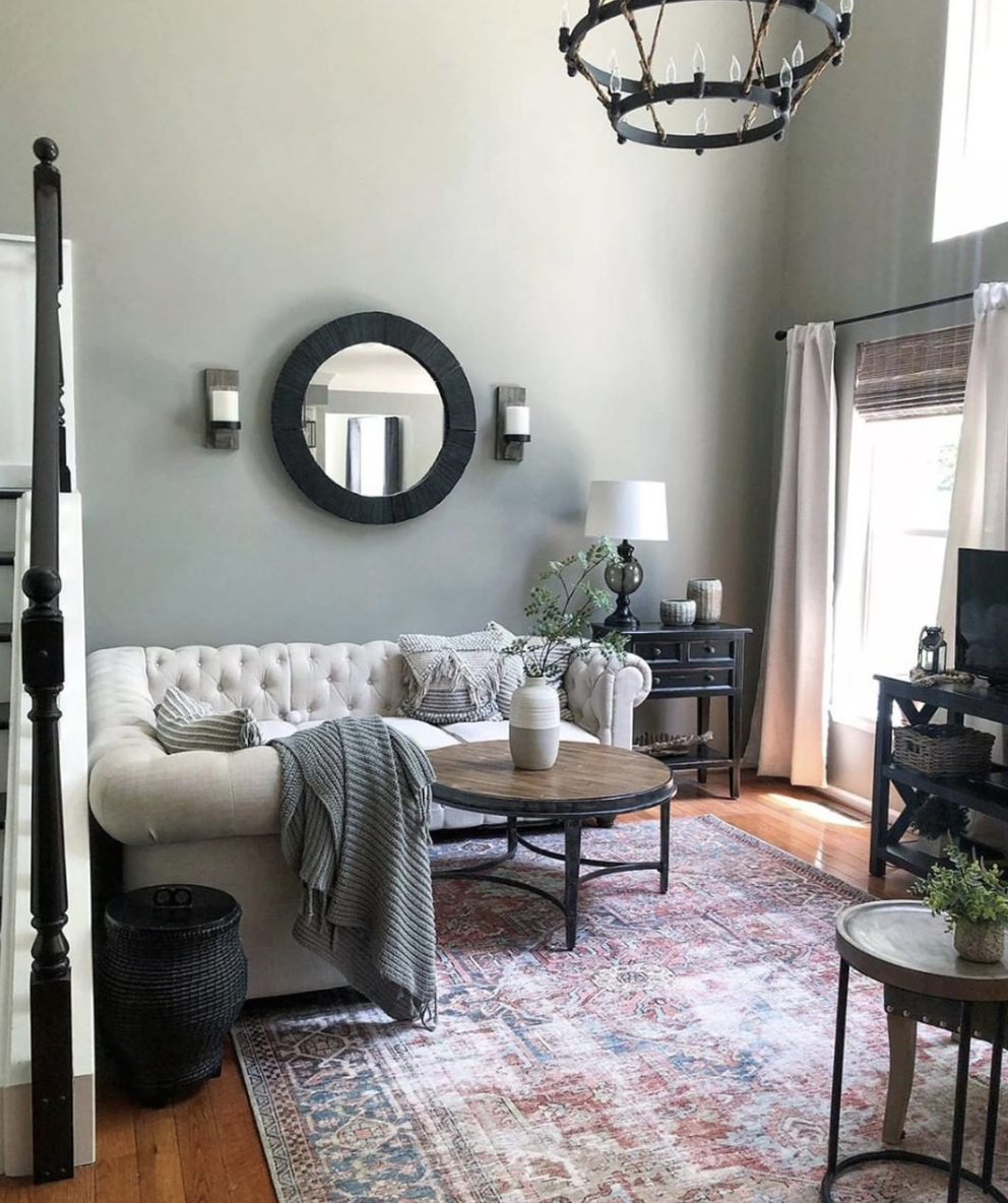 CC and Mike labor day sales terracotta loren rug in a living room with a gray chesterfield couch sofa and a sage green wall color with a round wood coffee table