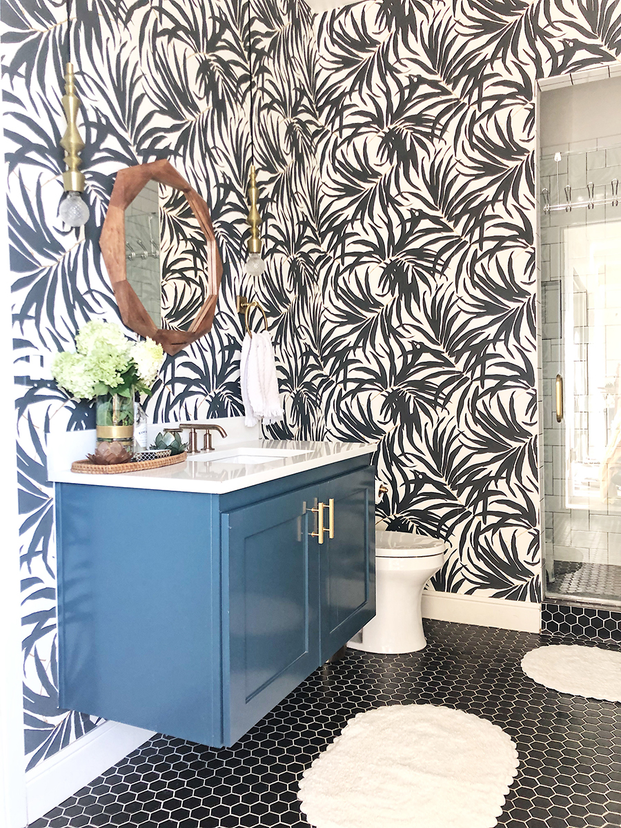 Vintage Chic Bathroom Update black hexagon floors with a green floating vanity and a wood mirror palm frond wallpaper