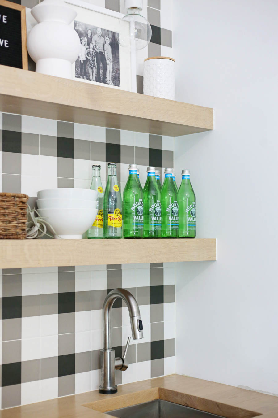 CC and Mike Frisco I Project Reveal black and white buffalo plaid check tile with open wood shelving in a game room bar stainless steel sink with butcher blog countertops