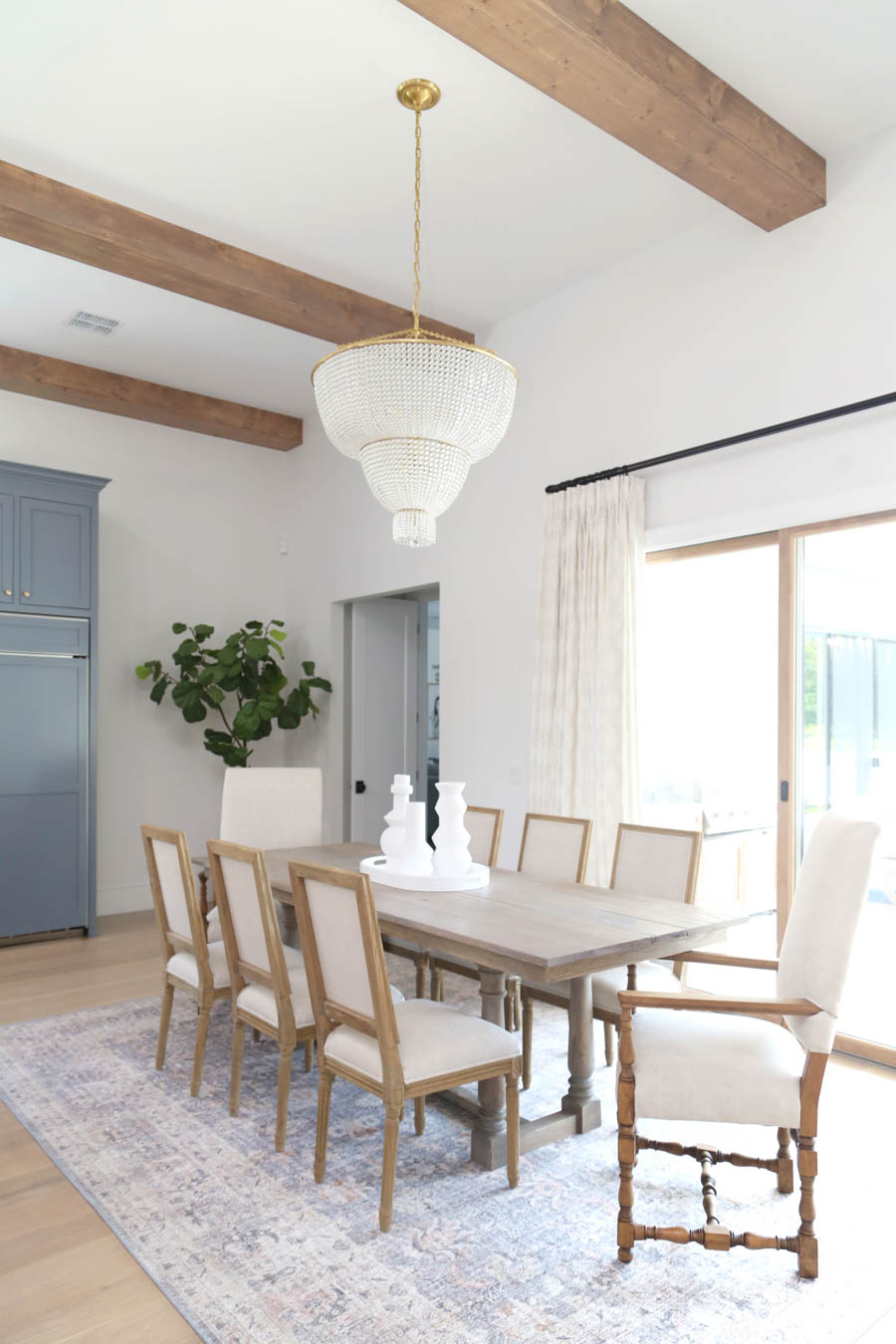 CC and Mike Frisco I Project Reveal-63 gray kitchen island and cabinets with wood bar stools quartz countertops and gold lanterns large kitchen window with gold sconces hidden pantry open floorpan dining room to gray kitchen with gold hardware wood farmhouse table and gold beaded chandelier