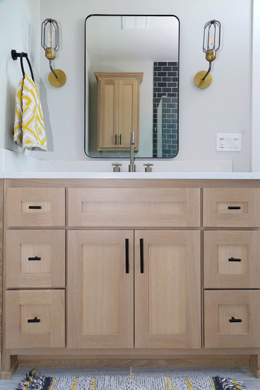 CC and Mike Frisco I Project Reveal black slate tile floors in a boys bathroom design with natural wood cabinets black hardware Franco bathroom mirror and gold and black sconces from CC and Mike THE SHOP 