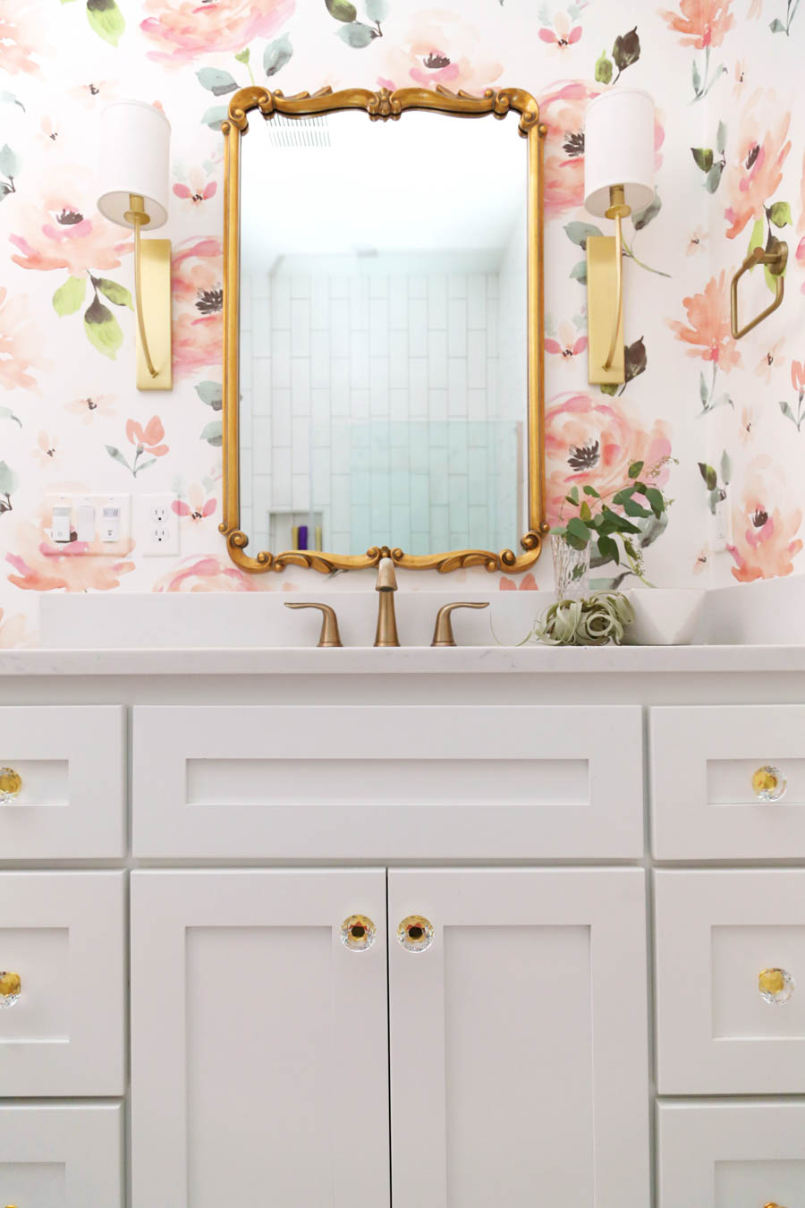 CC and Mike Frisco I Project Reveal modern girls bathroom design with floral Anthropologie wallpaper white cabinets gold Tolouse mirror acrylic and gold hardware on a white bathroom vanity and white hexagon floors