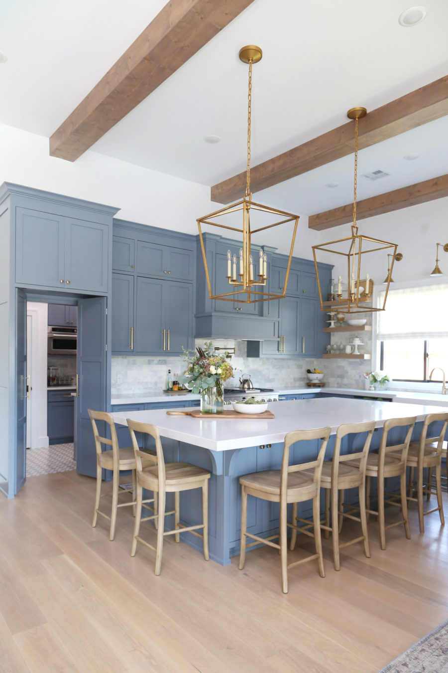 CC and Mike Frisco I Project Reveal-63 gray kitchen island and cabinets with wood bar stools quartz countertops and gold lanterns large kitchen window with gold sconces hidden pantry