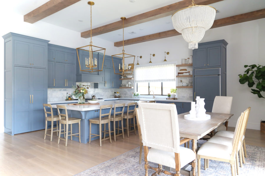 CC and Mike Frisco I Project Reveal-63 gray kitchen island and cabinets with wood bar stools quartz countertops and gold lanterns large kitchen window with gold sconces hidden pantry open floorpan dining room to gray kitchen with gold hardware wood farmhouse table and gold beaded chandelier