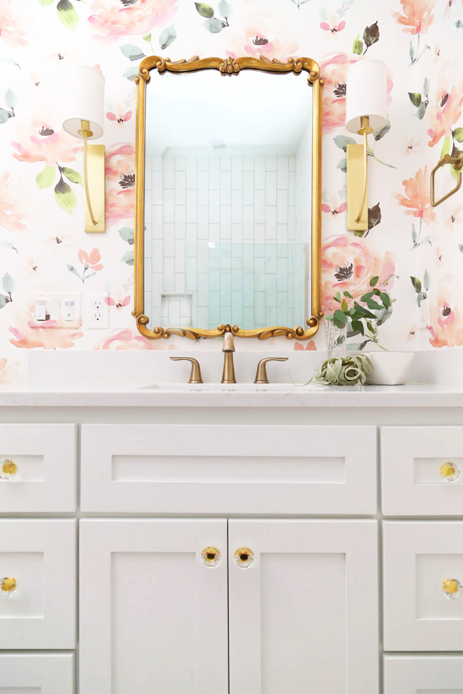 CC and Mike Frisco I Project Reveal modern girls bathroom design with floral Anthropologie wallpaper white cabinets gold Tolouse mirror acrylic and gold hardware on a white bathroom vanity and white hexagon floors