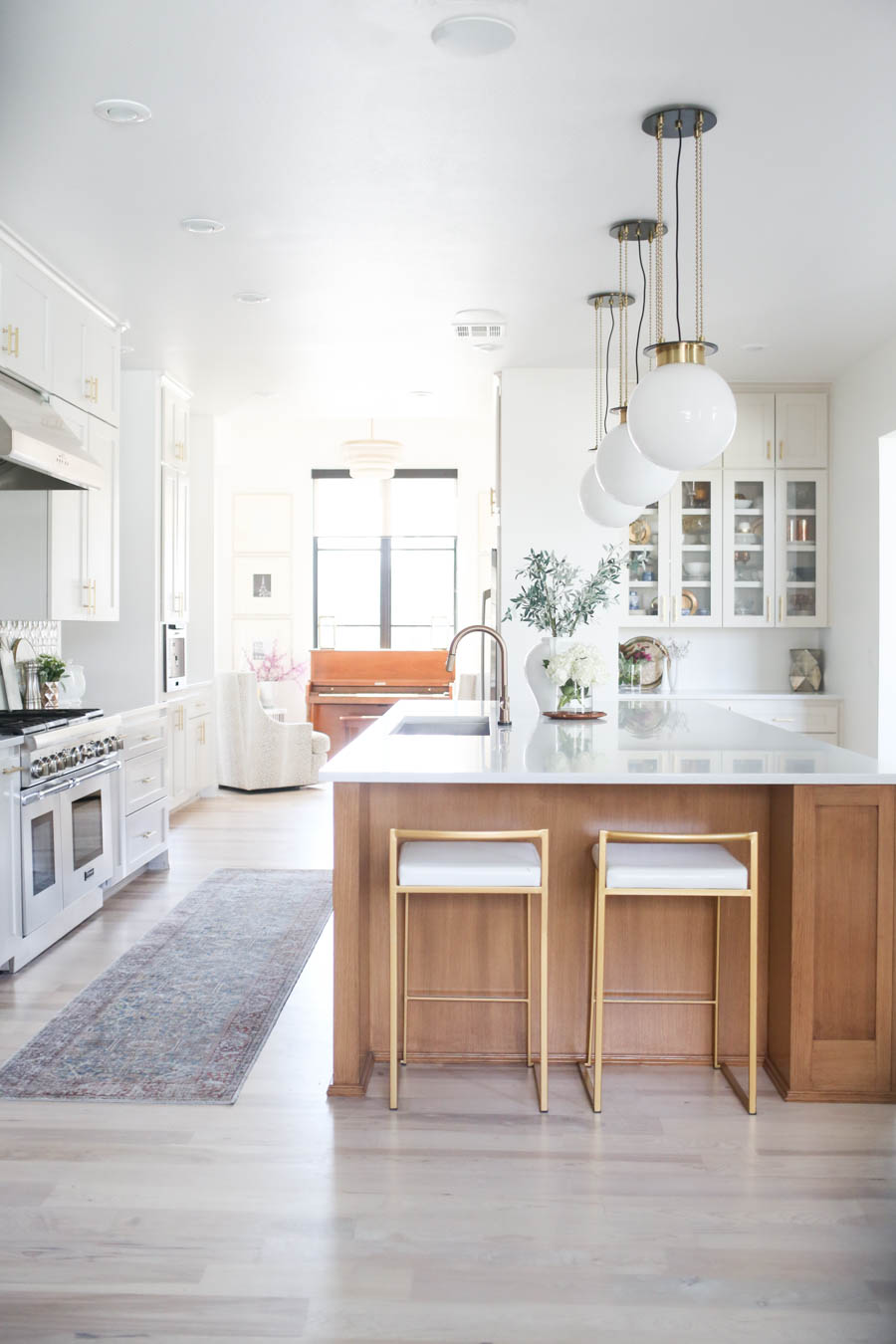 CC and MIke Kitchen Remodel Reveal large natural wood island with quartz countertops and gold bar stools black and gold pendants Ann sacks patterned backsplash gold Brizo faucet large Kallista stainless steel sink open floorpan